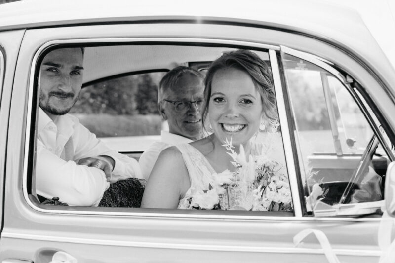 Braut ist fröhlich im Brautauto.