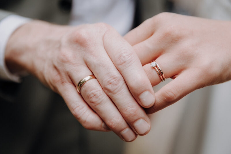 Detailaufnahme der Hände mit den Eheringen.