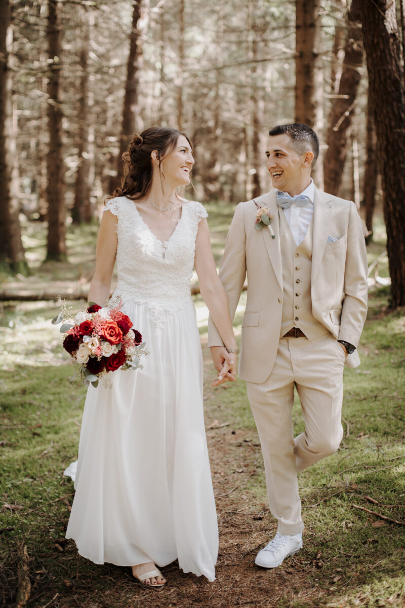 Brautpaar spaziert Hand in Hand im Wald des Filzenklas