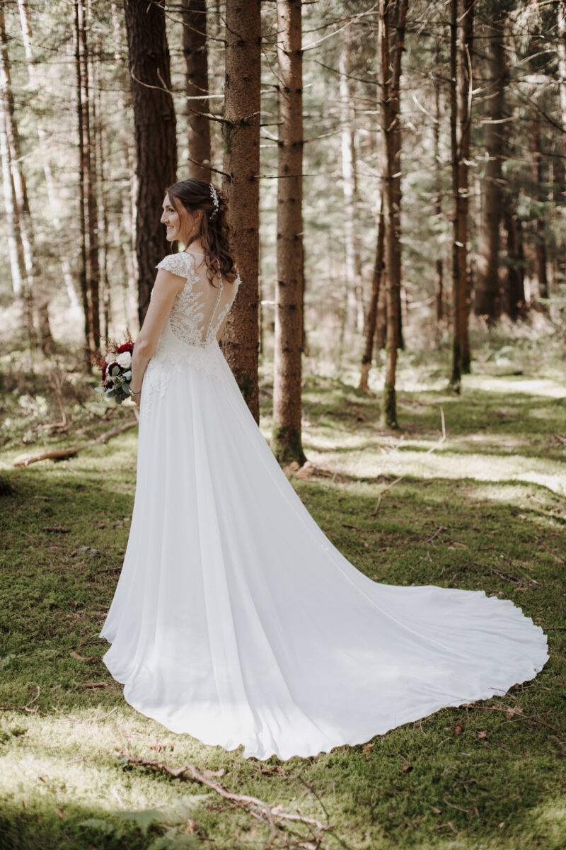 Braut seitlich im weißen Kleid im Wald des Filzenklas