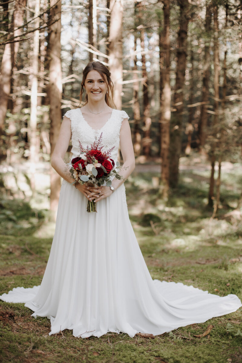 Braut von vorne im weißen Kleid im Wald des Filzenklas