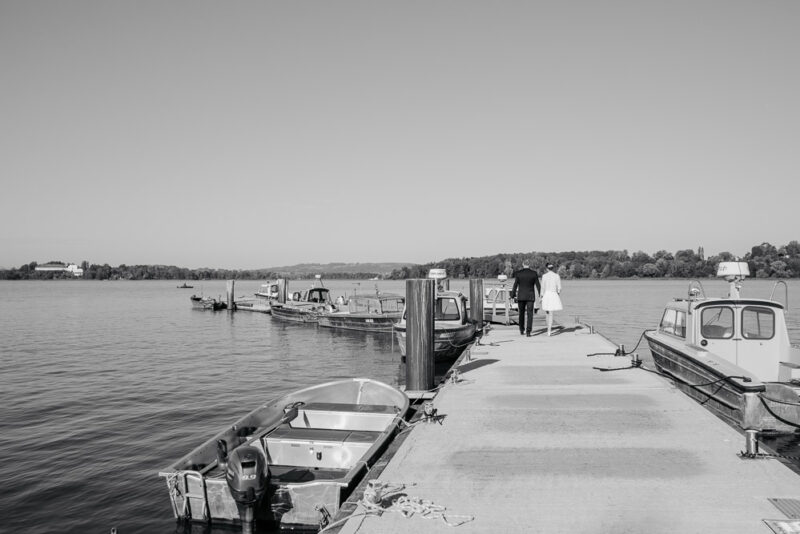 Brautpaar Hand in Hand auf einem Steg am Chiemsee.