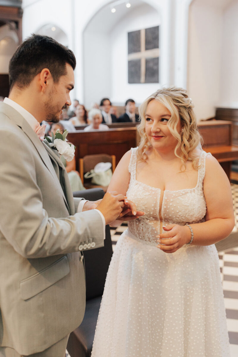 Brautpaar steckt sich die Ringe während der Trauung in der Erlöserkirche Rosenheim an