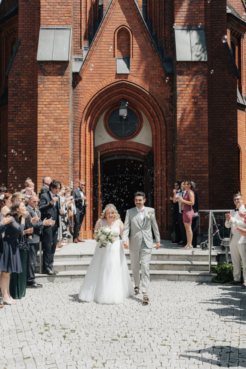 Brautpaar verlässt die Erlöserkirche Rosenheim und geht durch ein Spalier von Gästen