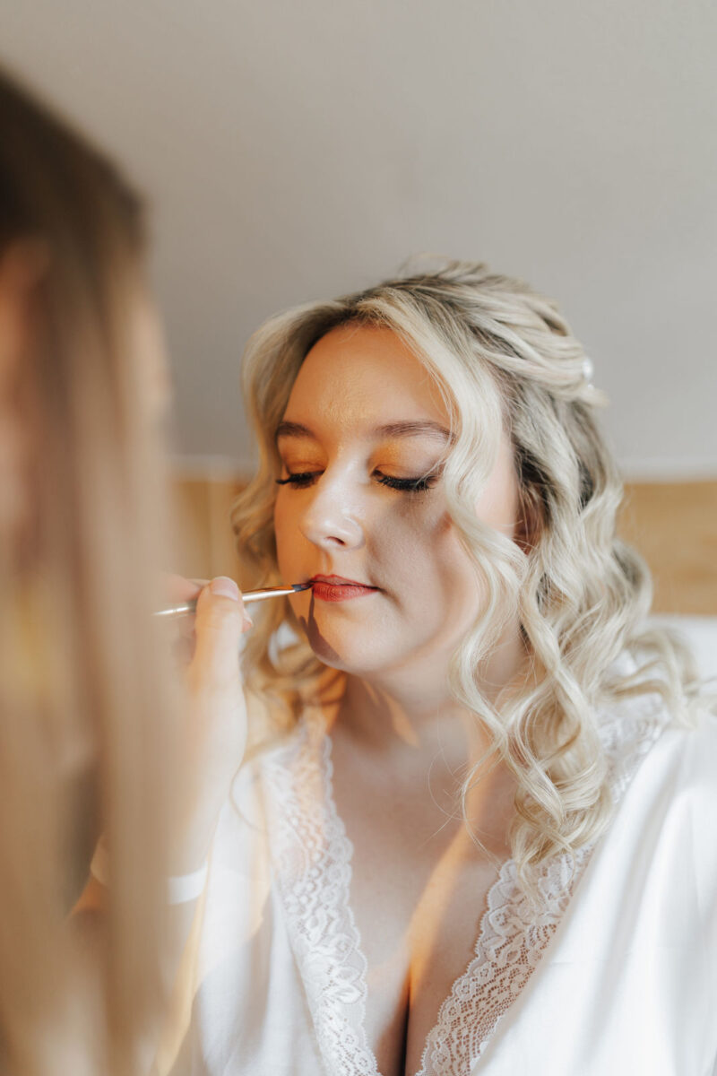 Stylist schminkt Braut beim Getting Ready am Hochzeitstag