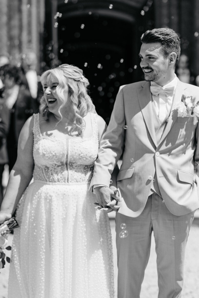 Brautpaar verlässt die Erlöserkirche Rosenheim und geht durch ein Spalier von Gästen