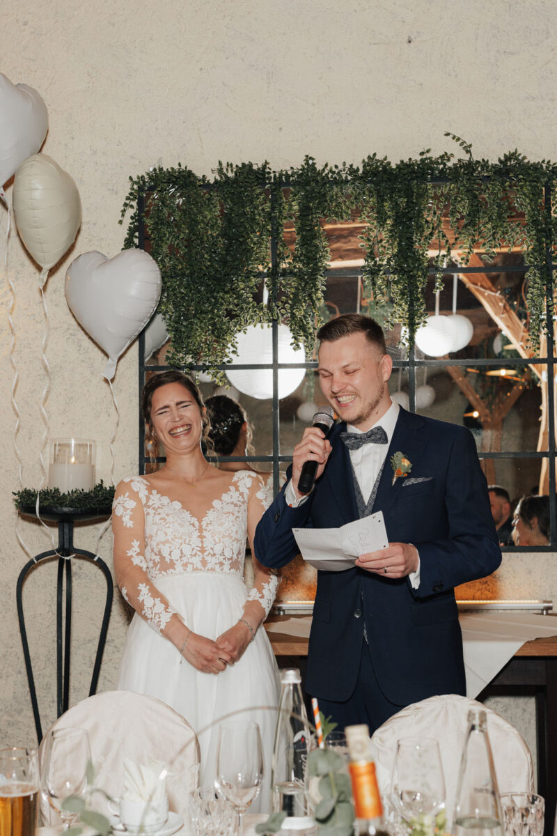 Rede des Bräutigams während der Hochzeitsfeier an der Mühle in Holzham, Braut lacht ausgelassen