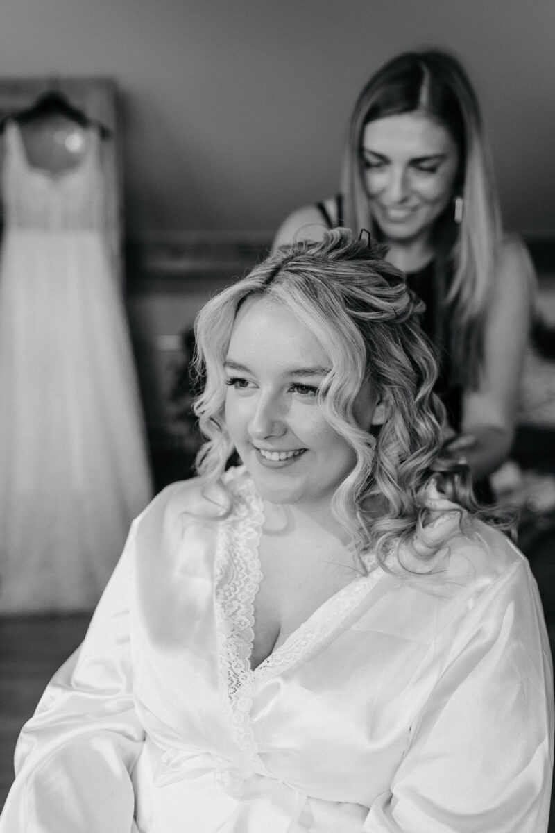 Stylist frisiert Braut beim Getting Ready am Hochzeitstag