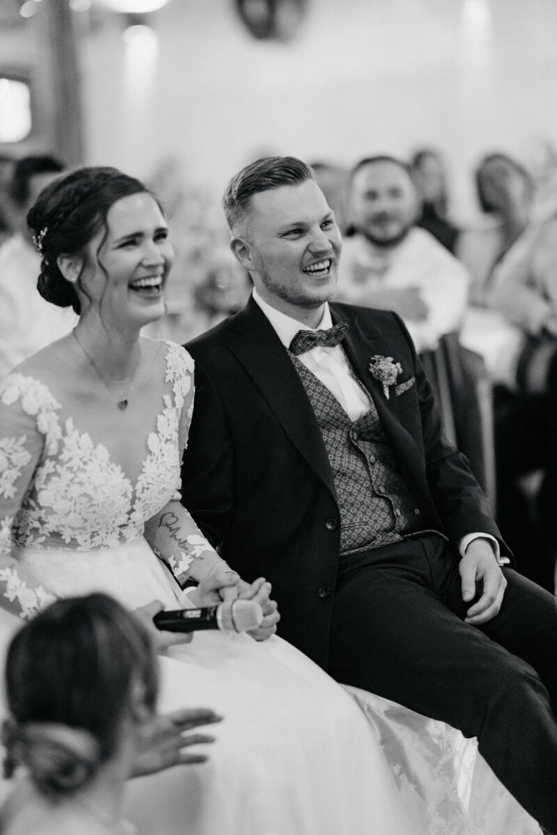 Brautpaar lacht gemeinsam während einer Diashow auf der Hochzeit
