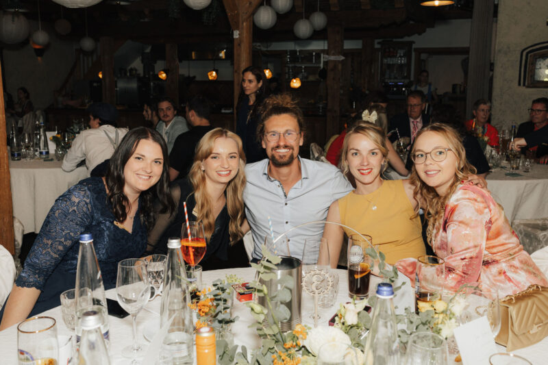 Hochzeitsfotografin fotografiert Gäste am Tisch im Hochzeitssaal