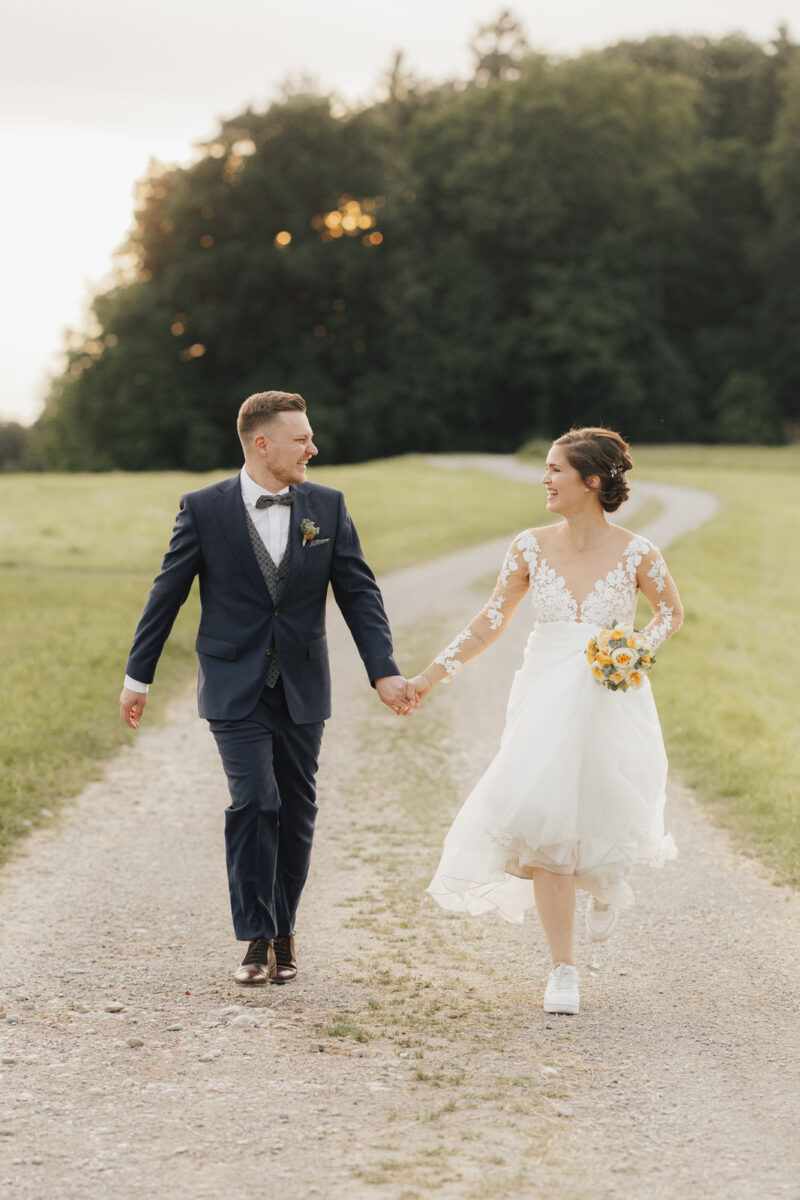 Brautpaar läuft und lacht sich an beim Brautpaarshooting zum Sonnenuntergang