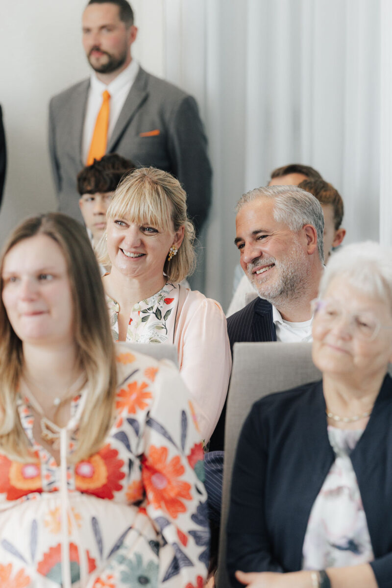 Gäste strahlen zum Brautpaar während der Trauung