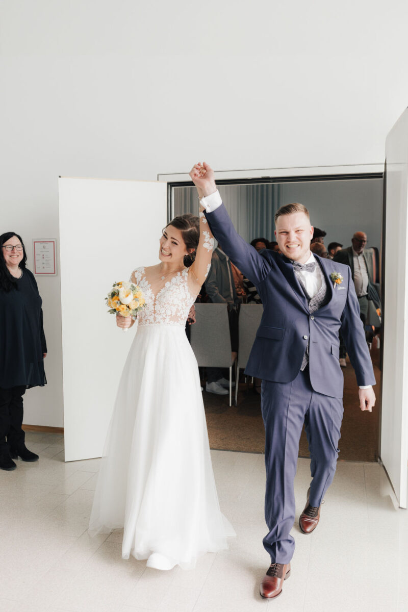 Braut und Bräutigam gehen nach der Trauung Hand in Hand aus dem Trausaal in Bad Aibling